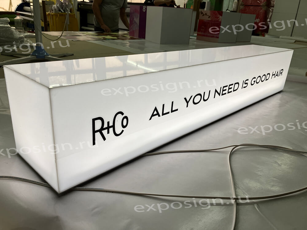 Белый прямоугольный световой куб с логотипом R+CO и слоганом "All You Need Is Good Hair" с LED-подсветкой и кабелем питания